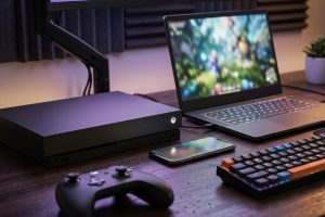 Консоль, ноутбук и смартфон на игровом столе для кроссплатформенной игры