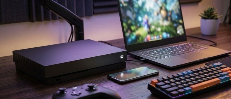 Консоль, ноутбук и смартфон на игровом столе для кроссплатформенной игры